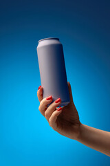 Woman hand holding gray aluminum beverage can for soda, beer, energy drinks, against vibrant...