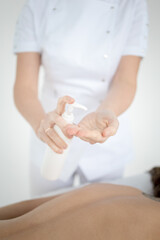 Closeup of masseur hands pouring aroma oil on woman back. Masseuse prepare to do oriental spa procedure for relaxing treatment. Therapist doing aromatherapy oil massage on woman body.