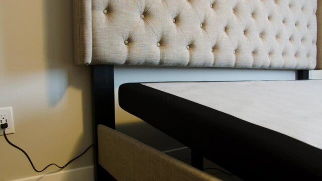 Close up of electronic bed power base corner descending upholstered headboard wall outlet