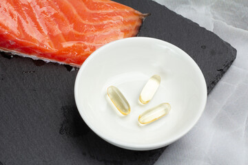 Fillet of raw salmon fish with capsules of fish oil on the cutting board