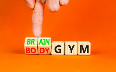 Body vs brain gym symbol. Businessman turns wooden cubes and changes words Body gym to Brain gym. Beautiful orange table orange background, copy space. Business and body vs brain gym concept.