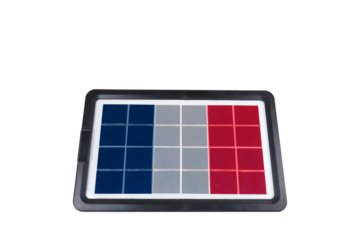 Portable solar panel in the shape of the flag of France isolated on white background (close-up). Concept of developing renewable green alternative energy in France