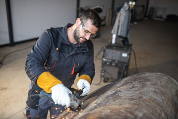 Metal worker using angle grinder creating sparks in workshop