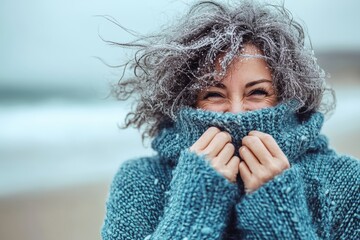 Standing at the seaside is a middle-aged grey-haired woman smiling confidently