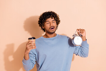 Photo of tired sleepy guy with wavy hairdo wear blue shirt hold cup of latte clock early morning...
