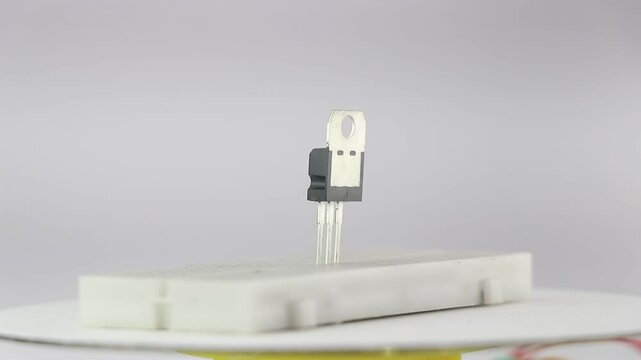 View of field effect transistor connected to a prototyping board rotating and is isolated on white background