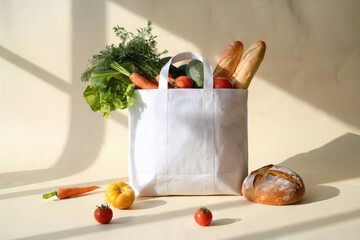 Reusable white bag overflowing with fresh vegetables and bread on a cream background with natural lighting and soft shadows creating a wholesome aesthetic
