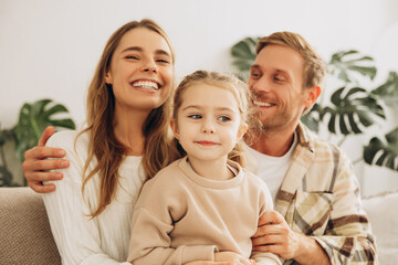 Portrait of beautiful, smiling family, little daughter, mom and father embracing together