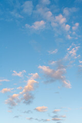 Blue sky and floating cotton clouds in sunlight