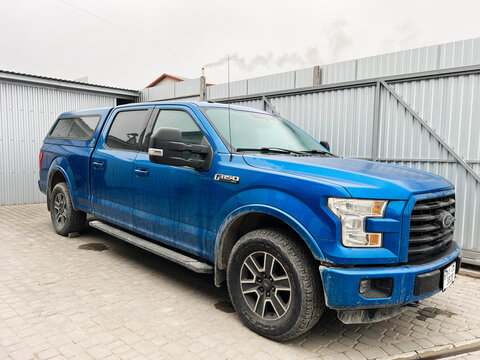 Kyiv, Ukraine - November 22, 2024: Blue pickup Ford F 150 truck parked near industrial metal fence outdoors