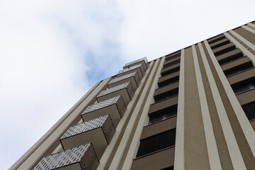 Urban architecture showcases a tall and striking building standing against a cloudy blue sky backdrop