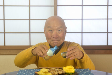 和室でリラックスしてお酒を飲んでいるおじいちゃん