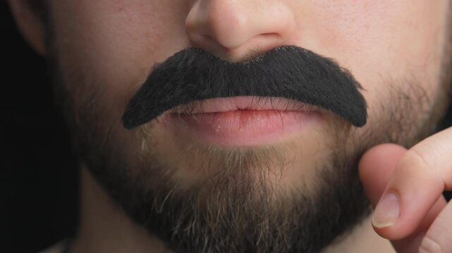 Young man, practical joker peels off a fake mustache to reveal real mustache