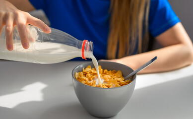 Wlewać świeże mleko z butelki do miski z płatkami śniadaniowymi 