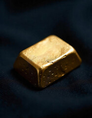 Gold bar resting on a dark surface showcasing its shine and intricate details