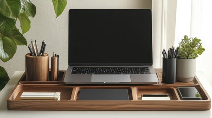 A laptop sits on a wooden tray with a potted plant next to it