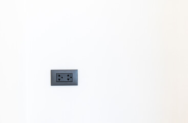 electric plug on wall, black colour plug on white wall background, twins holes plug on white background.