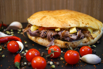 Meat Tombik Doner Kebab Sandwich with tomato, garlic, red pepper isolated on dark background closeup side view of turkish fast food