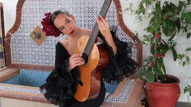 Spanish flamenco woman playing spanish guitar in andalusia patio