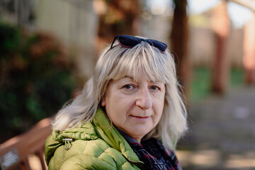 Close up portrait of grandmother outdoors in autumn wearing cozy sweater thoughtful expression...
