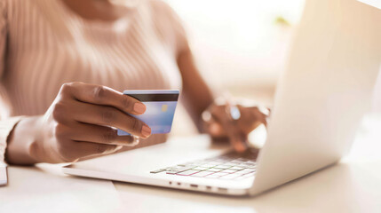Fototapeta premium Woman Holding Credit Card in Front of Laptop, Engaged in Online Shopping or Banking, Bright Workspace Setting, Modern Lifestyle Concept, Financial Technology Use