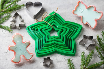 Assorted Christmas cookie cutters with Christmas tree branches on grey textured background