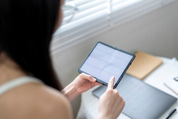 Young woman using digital tablet with blank screen at home office