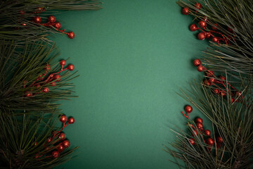 Christmas green background with pine bracnhes and holly red berries
