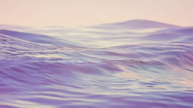 Camera pans across muted, pastel ocean waves in this establishing video. smooth, undulating water in pink, blue, and purple creates hypnotic motion.