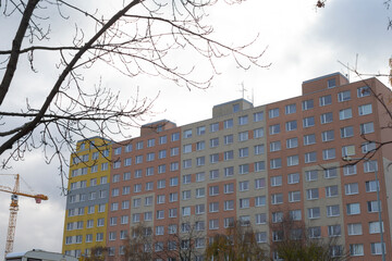 A remarkably tall residential building featuring a distinct yellow section, set against a cloudy gray sky