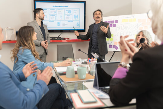 Diverse business team discussing startup strategy using business model canvas presentation during creative meeting in modern office