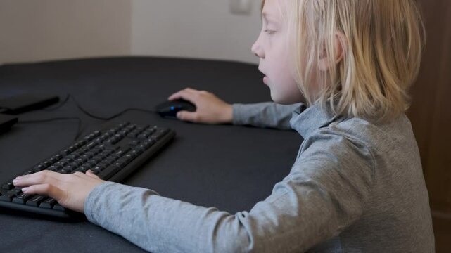 Slow motion video of a young boy playing video games on a computer