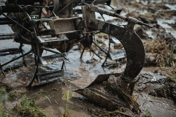 Closeup of machinery plowing muddy farmland to prepare for the upcoming crop season
