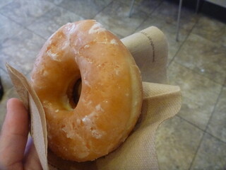 Hand holding original glazed donut in a napkin