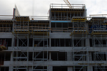 A construction scene illustrates scaffolding prominently situated with a large building seen in the distance