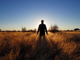 Silhouette of a man walking on the savanna during a sunrise
