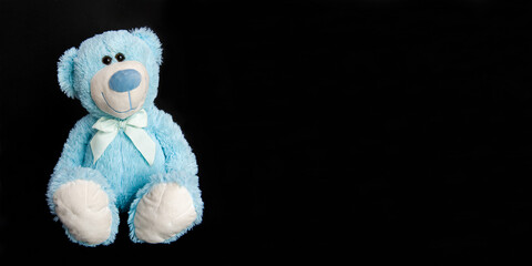Blue teddy bear on a black background. Children's toy,Teddy bear, isolated on black, sitting bear, space for text