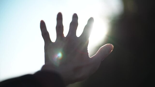 太陽に向かって手をのばす男性