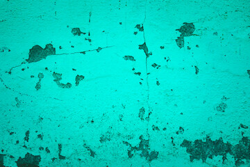 A wall with a green background and a blue wall. The wall has a lot of cracks and holes