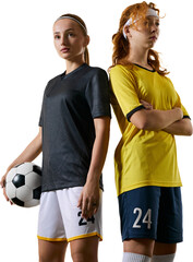 Athletic young women, soccer players, standing back-to-back. One holding ball, both displaying...