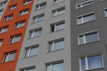 The facade of an apartment building showcases vibrant orange and gray backgrounds adding depth and character