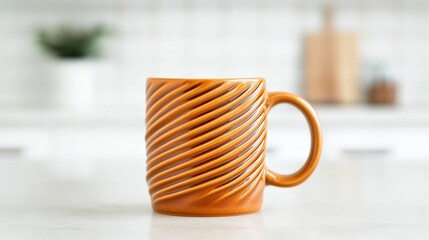Obraz premium Handmade Ceramics concept. A beautifully crafted orange mug with a spiraled texture, set against a clean kitchen background, perfect for enjoying warm beverages.