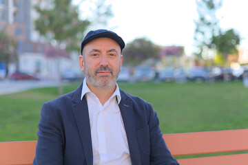 Man sitting on a bench in the park calm and smiling