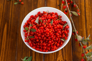 fresh ripe red goji berries in a bowl on a wooden table