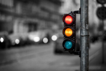 view of city traffic with traffic lights, in the foreground a semaphore with a red and orange light