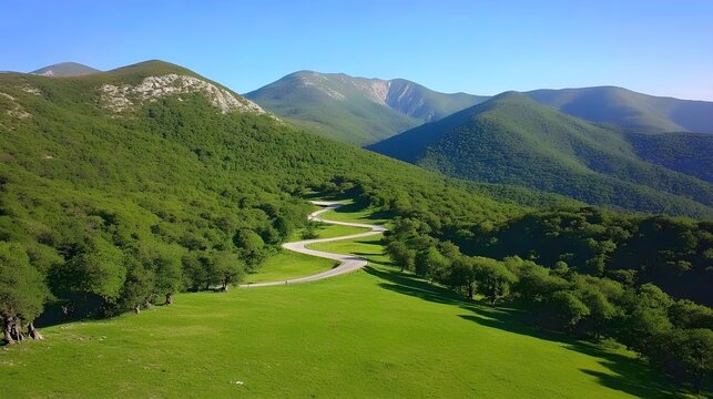 Serene Summer View of High Mountains in Gex Region with Winding Road Through Lush Green Landscape and Clear Blue Skies