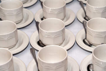Empty white tableware crockery cups and saucers arranged on a table at a formal hospitality banqueting event or wedding, banquet stock photo image
