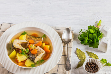 Clear Pike soup with veggies and spices, top view