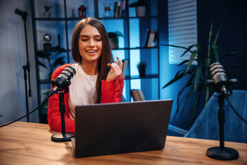 Woman is hosting radio podcast with microphone and laptop