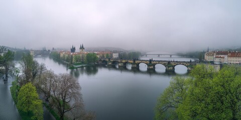 Obraz premium Prague's Old Town, seen from above in spring, shows the Charles Bridge arching over the Vltava River. The castle is visible in the distance.